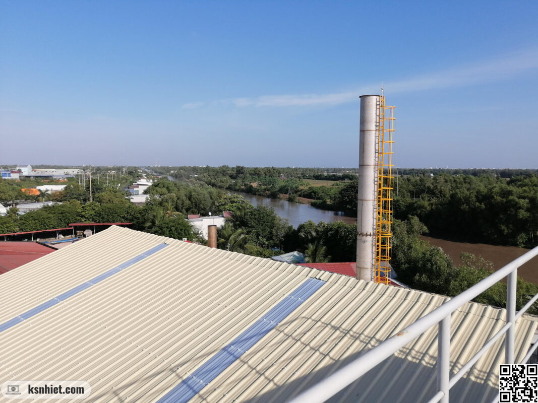 Ống khói lò hơi thải ra khói sạch giữa không xanh cây cối xanh