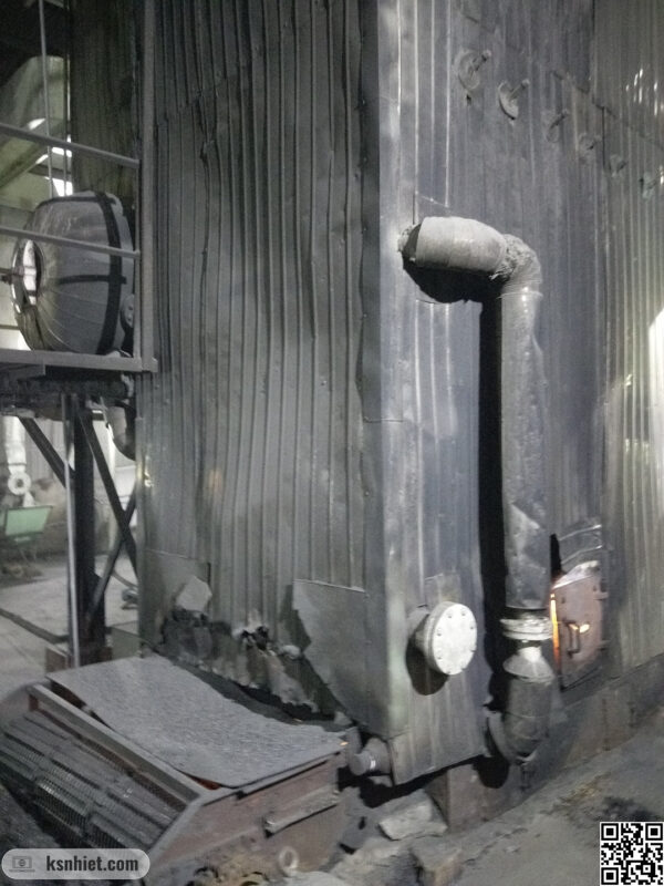 Lò hơi cũ đang hoạt động, với các lớp bảo ôn bị xuống cấp, cửa thao tác bị phì lửa ra bên ngoài