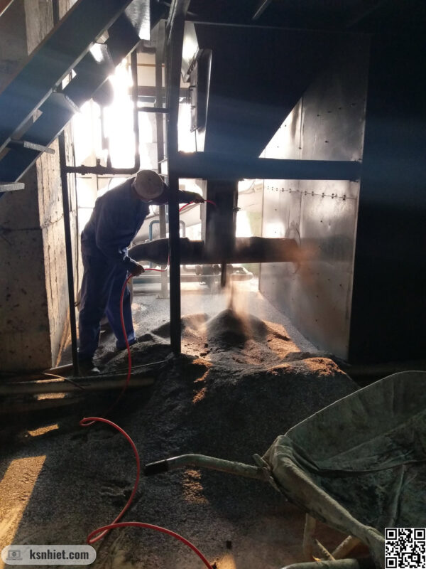 Sự cố tro nhiều trong lò hơi: Bí quyết tối ưu hiệu suất và biến "phế thải" thành tài nguyên vàng 6 Người công nhân đang vệ sinh bụi định kỳ trong phễu tro buồng đốt